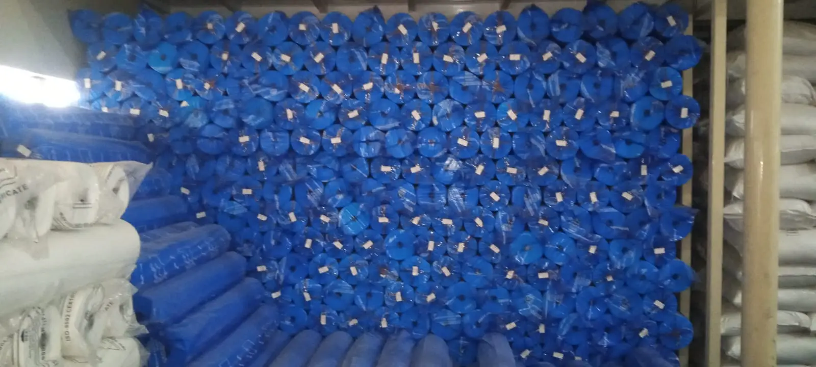 Wall of blue non-woven sachet fabric rolls in the DryGelWorld warehouse